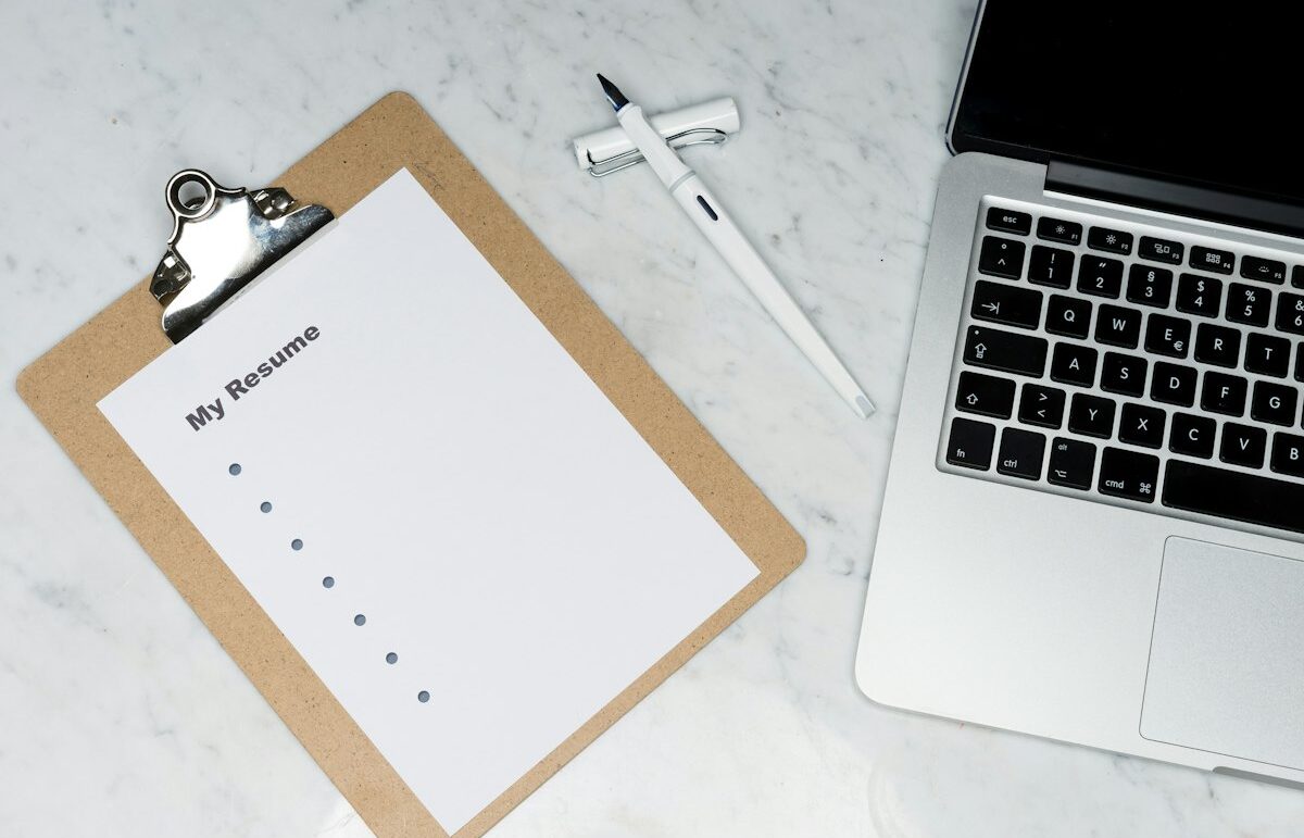 Resume on a clipboard next to a laptop